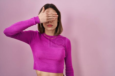 Photo for Hispanic woman standing over pink background covering eyes with hand, looking serious and sad. sightless, hiding and rejection concept - Royalty Free Image