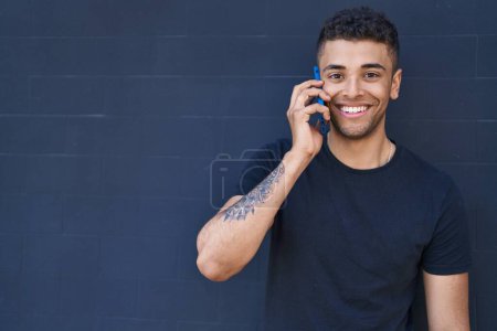 Foto de Hombre afroamericano sonriendo confiado hablando en el teléfono inteligente sobre fondo negro - Imagen libre de derechos