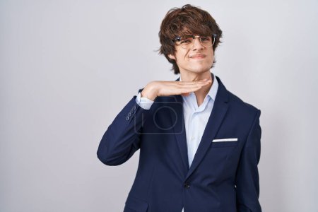 Foto de Joven empresario hispano con gafas que cortan la garganta con la mano como cuchillo, amenazan la agresión con violencia furiosa - Imagen libre de derechos