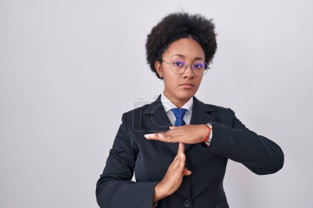 Photo for Beautiful african woman with curly hair wearing business jacket and glasses doing time out gesture with hands, frustrated and serious face - Royalty Free Image
