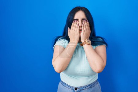 Photo for Young modern girl with blue hair standing over blue background rubbing eyes for fatigue and headache, sleepy and tired expression. vision problem - Royalty Free Image