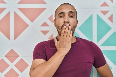 Photo for Hispanic man with beard standing over colorful wall covering mouth with hand, shocked and afraid for mistake. surprised expression - Royalty Free Image