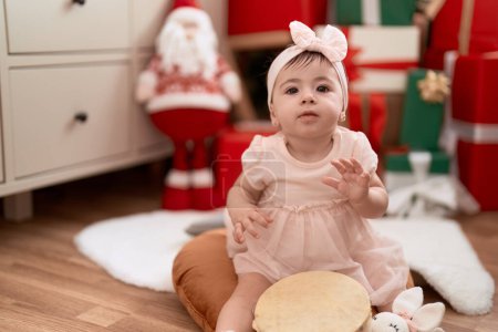 Foto de Adorable niño jugando pandereta sentado en el suelo por regalo de Navidad en casa - Imagen libre de derechos