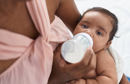 Téléchargez les photos : African american baby sucking feeding bottle at bedroom - en image libre de droit