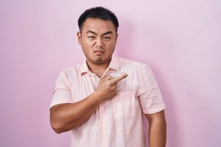 Photo for Chinese young man standing over pink background pointing aside worried and nervous with forefinger, concerned and surprised expression - Royalty Free Image