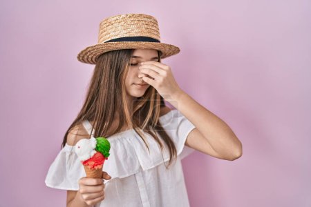 Foto de Teenager girl holding ice cream tired rubbing nose and eyes feeling fatigue and headache. stress and frustration concept. - Imagen libre de derechos