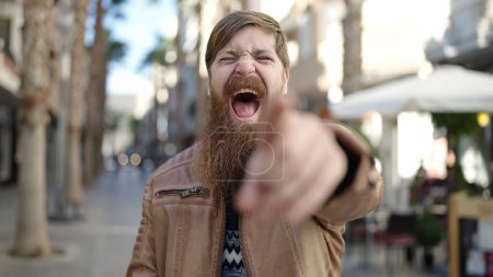Téléchargez les photos : Young redhead man smiling confident pointing with finger at coffee shop terrace - en image libre de droit