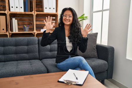 Photo for Young asian woman at consultation office showing and pointing up with fingers number ten while smiling confident and happy. - Royalty Free Image