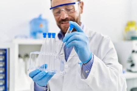 Foto de Hombre hispano de mediana edad vistiendo uniforme científico trabajando en laboratorio - Imagen libre de derechos