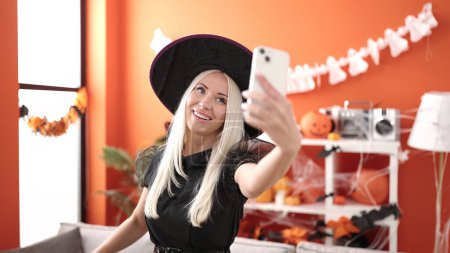 Foto de Young blonde woman make selfie by smartphone having halloween party at home - Imagen libre de derechos