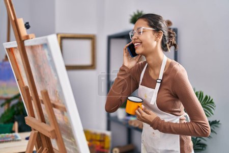Foto de Young african american woman artist talking on the smartphone drinking coffee at art studio - Imagen libre de derechos