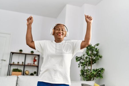 Foto de Mujer afroamericana mayor sonriendo confiada y bailando en casa - Imagen libre de derechos
