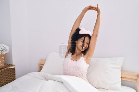 Foto de Mujer hispana joven despertando con los brazos extendidos en el dormitorio - Imagen libre de derechos