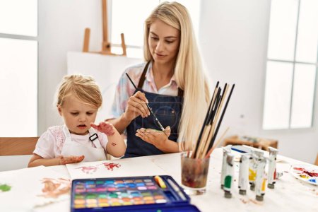 Téléchargez les photos : Mère et fille souriant confiantes mains de palmier peinture au studio d'art - en image libre de droit