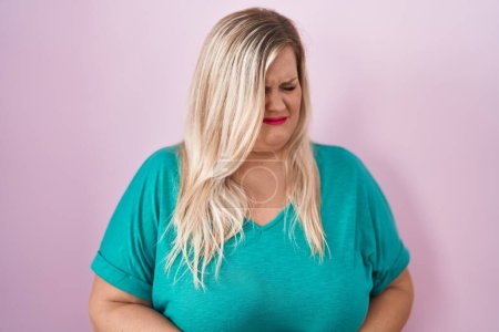Foto de Caucasian plus size woman standing over pink background with hand on stomach because indigestion, painful illness feeling unwell. ache concept. - Imagen libre de derechos