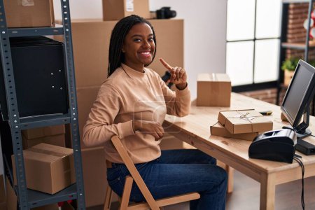 Foto de Young african american with braids working at small business ecommerce smiling happy pointing with hand and finger - Imagen libre de derechos