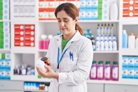 Téléchargez les photos : Young woman pharmacist scanning pills bottle at pharmacy - en image libre de droit