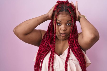 Photo for African american woman with braided hair standing over pink background crazy and scared with hands on head, afraid and surprised of shock with open mouth - Royalty Free Image