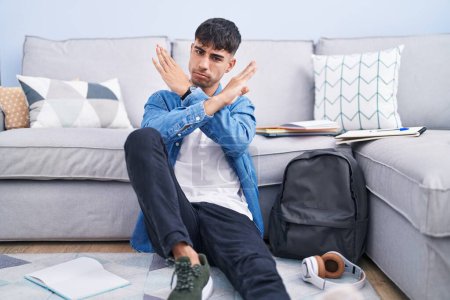 Téléchargez les photos : Young hispanic man sitting on the floor studying for university rejection expression crossing arms doing negative sign, angry face - en image libre de droit