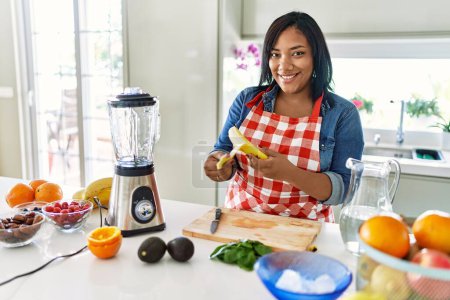 Photo for Hispanic brunette woman preparing fruit smoothie at the kitchen - Royalty Free Image