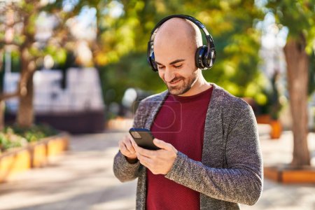 Téléchargez les photos : Jeune homme souriant confiant écoutant de la musique au parc - en image libre de droit
