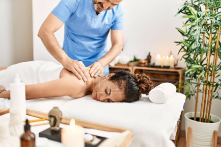 Téléchargez les photos : Homme et femme d'âge moyen portant l'uniforme de thérapeute ayant la session de massage du dos au centre de beauté - en image libre de droit