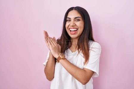 Téléchargez les photos : Jeune femme arabe debout sur fond rose applaudissements et applaudissements heureux et joyeux, souriant mains fiers ensemble - en image libre de droit
