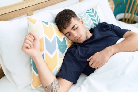 Téléchargez les photos : Jeune homme hispanique couché sur le lit dormant dans la chambre - en image libre de droit