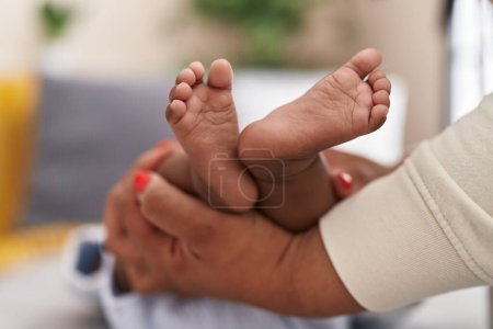 Photo for African american baby lying on bed having legs massage at home - Royalty Free Image