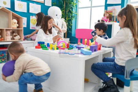 Photo for Group of kids playing with construction blocks sitting on table at kindergarten - Royalty Free Image