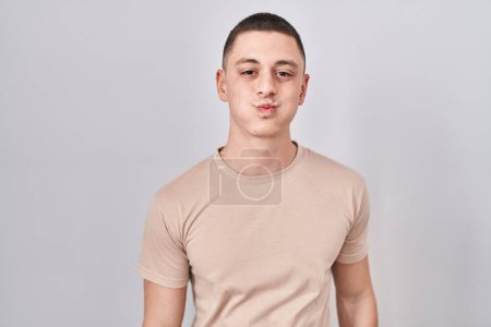 Téléchargez les photos : Young man standing over isolated background puffing cheeks with funny face. mouth inflated with air, crazy expression. - en image libre de droit