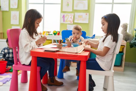 Téléchargez les photos : Group of kids preschool students sitting on table drawing and make handcrafts at kindergarten - en image libre de droit