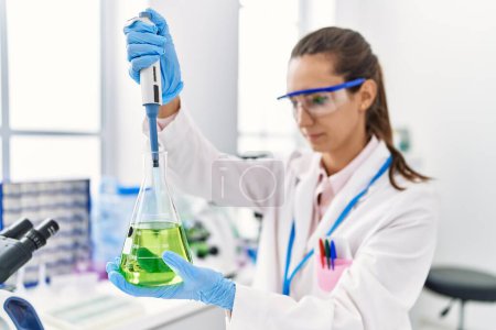 Photo for Young hispanic woman wearing scientist uniform using pipette and test tube working at laboratory - Royalty Free Image