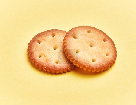 Téléchargez les photos : Delicious two salty biscuits over isolated yellow background - en image libre de droit