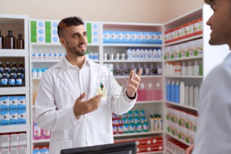 Téléchargez les photos : Two hispanic men pharmacist speaking to client at pharmacy - en image libre de droit