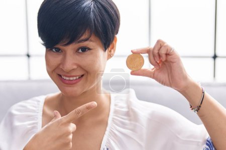 Téléchargez les photos : Young asian woman with short hair holding tron cryptocurrency coin smiling happy pointing with hand and finger - en image libre de droit