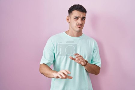 Photo for Handsome hispanic man standing over pink background disgusted expression, displeased and fearful doing disgust face because aversion reaction. - Royalty Free Image