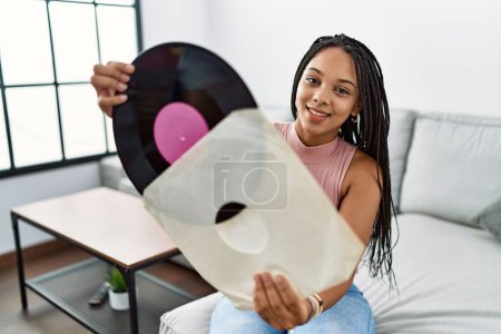 Téléchargez les photos : Jeune femme afro-américaine souriante confiante tenant un disque vinyle à la maison - en image libre de droit