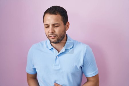 Téléchargez les photos : Homme hispanique debout sur fond rose avec la main sur le ventre parce que l'indigestion, la maladie douloureuse se sent mal. concept de douleur. - en image libre de droit