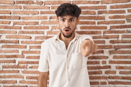 Photo for Arab man with beard standing over bricks wall background pointing displeased and frustrated to the camera, angry and furious with you - Royalty Free Image