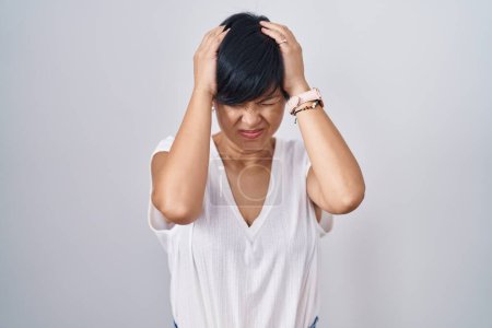 Photo for Young asian woman with short hair standing over isolated background suffering from headache desperate and stressed because pain and migraine. hands on head. - Royalty Free Image