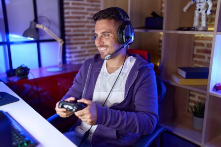 Photo for Young hispanic man streamer playing video game using joystick at gaming room - Royalty Free Image