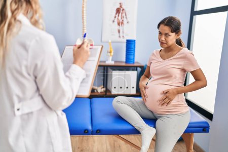 Téléchargez les photos : Jeune femme latine enceinte ayant une séance de physiothérapie à la clinique - en image libre de droit
