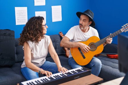 Photo for Man and woman musicians playing piano and classical guitar at music studio - Royalty Free Image