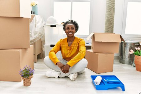 Foto de Mujer afroamericana sonriendo confiada sentada en el piso en un nuevo hogar - Imagen libre de derechos