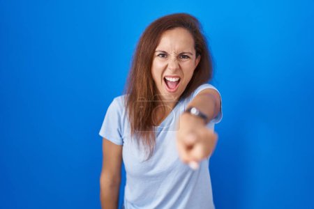 Photo for Brunette woman standing over blue background pointing displeased and frustrated to the camera, angry and furious with you - Royalty Free Image