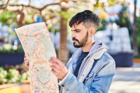 Téléchargez les photos : Jeune homme hispanique souriant confiant tenant la carte de la ville au parc - en image libre de droit