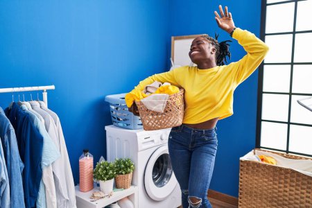 Photo for African american woman smiing confident holding basket with clothes at laundry room - Royalty Free Image