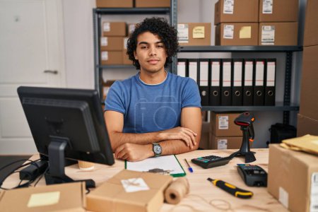 Téléchargez les photos : Hispanic man with curly hair working at small business ecommerce looking sleepy and tired, exhausted for fatigue and hangover, lazy eyes in the morning. - en image libre de droit