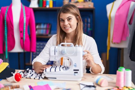 Téléchargez les photos : Young woman tailor smiling confident using sewing machine at sewing studio - en image libre de droit